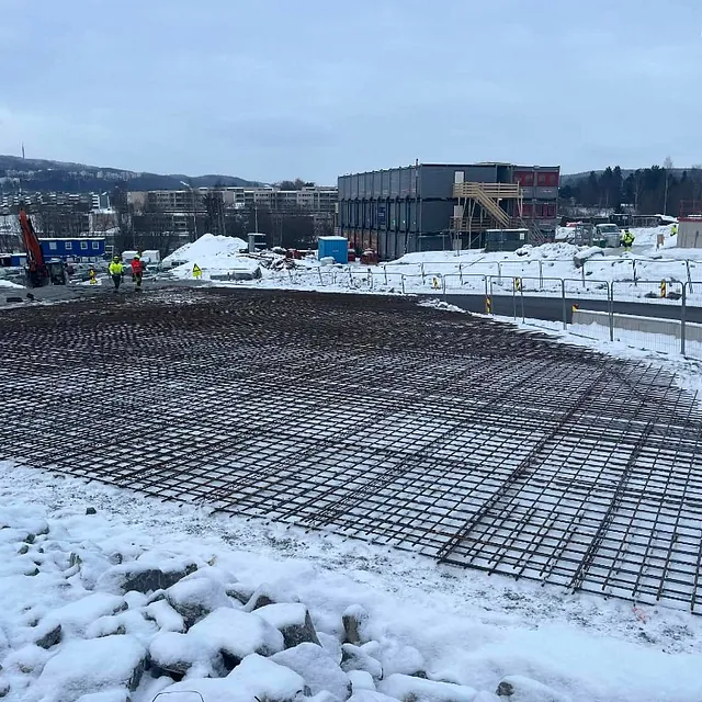 Armeringsjern lagt klart for betongplate i snødekt byggeområde