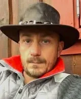Mann i mørk hatt og grå jakke